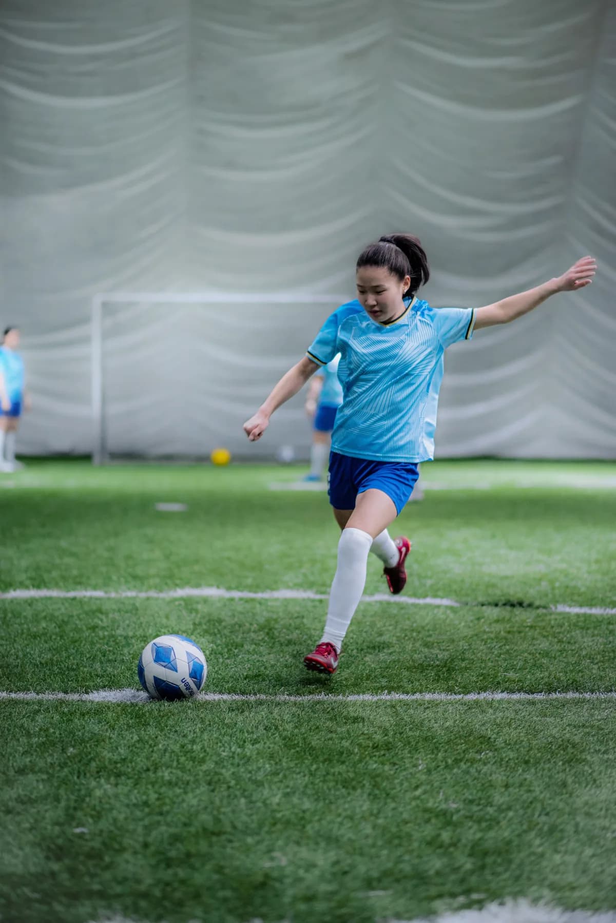 Player striking a football on an indoor pitch