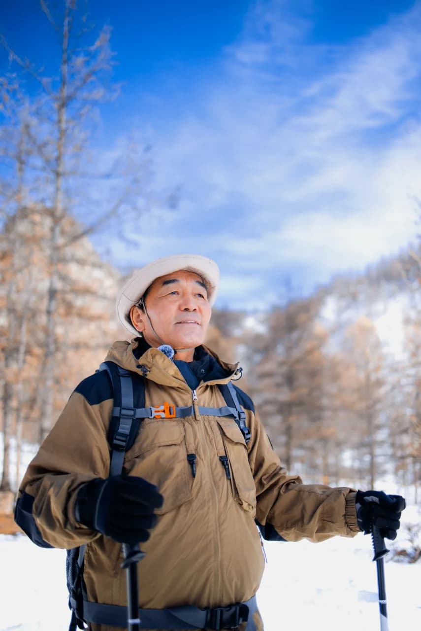 Hiker with trekking poles in a snowy Mongolian forest